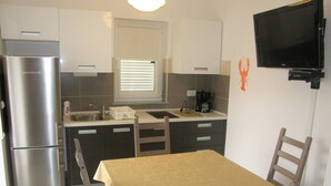 Una cocina compacta con refrigerador, lavamanos y cafetera.