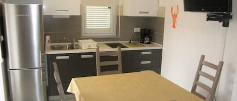 A compact kitchen with a refrigerator, sink, and a coffee maker.