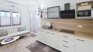 Une cuisine moderne avec des meubles blancs, un four encastré, un four à micro-ondes et un évier.