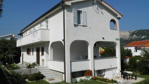 A two-story building with a white exterior, a satellite dish, and a balcony.