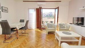 Un salon moderne comprenant un coin repas, un téléviseur et un balcon avec vue sur la montagne.