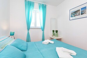 Ein Schlafzimmer mit Bett, Nachttisch, Spiegel und einem Fenster mit Vorhängen.