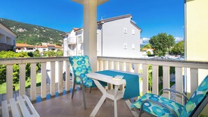 A balcony with a table and chairs, overlooking a residential area with houses and a mountain. - Apartment Lavendel - with Balcony, 250 m from the Beach (Baska)