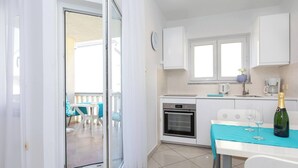 A modern kitchen with a built-in oven, a dining area with a table and chairs, and a balcony with a view. - Apartment Lavendel - with Balcony, 250 m from the Beach (Baska)