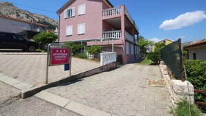 Un bâtiment rose doté d’un balcon, d’une enseigne et d’un trottoir dallé.