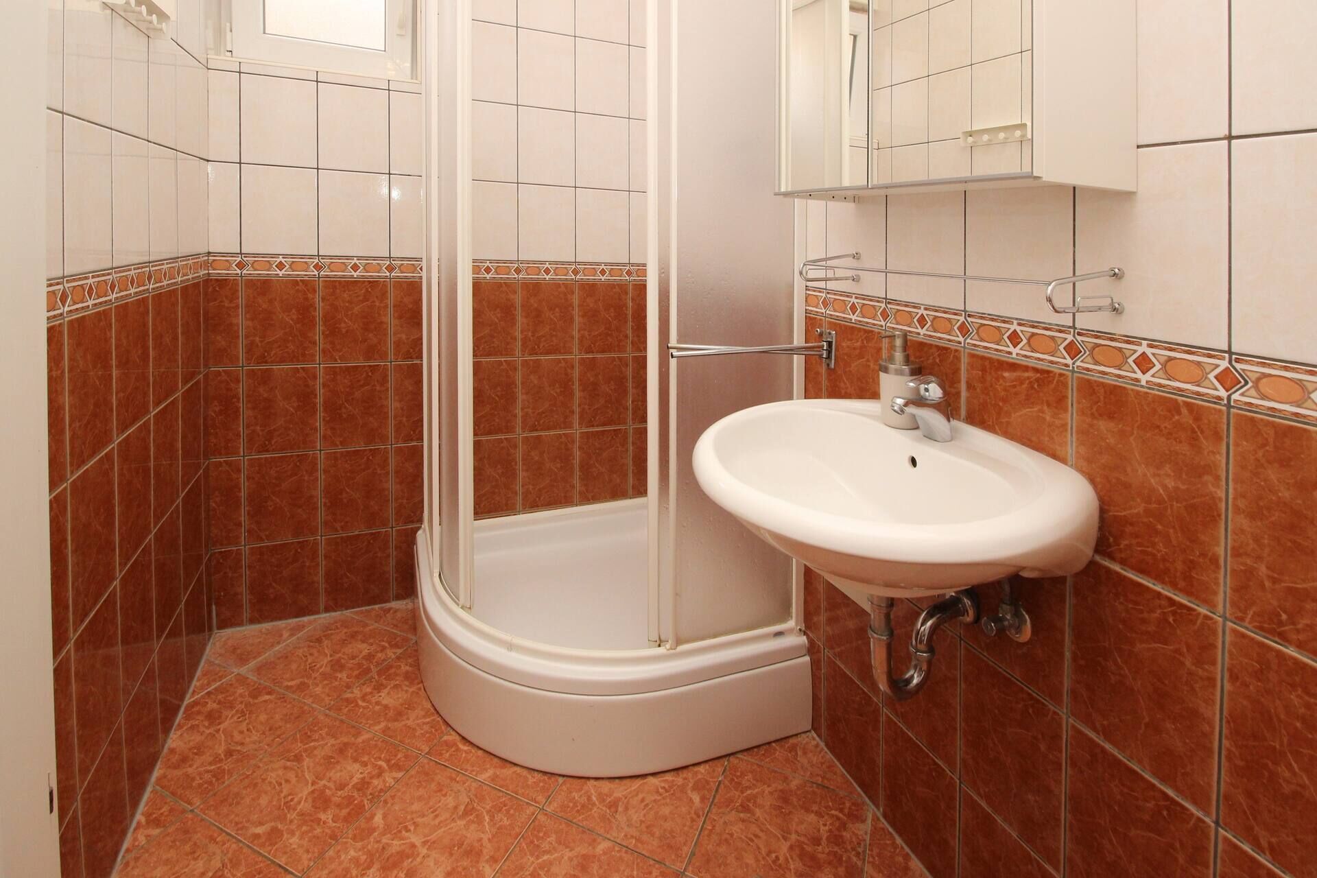 Un baño con ducha, lavamanos y espejo.