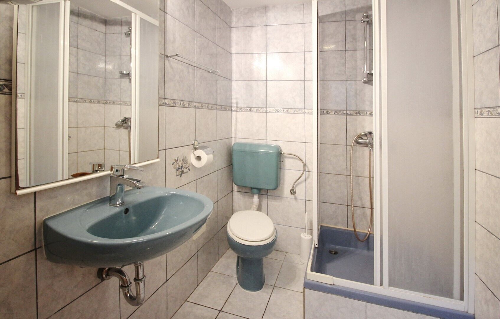 Et badeværelse med vask, toilet og brusebad.