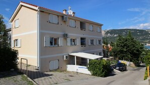 A multi-story building with a flat roof, multiple windows with shutters, and a satellite dish on the roof. - Apartments Mikulan Nara Priz - with Terrace, 350 m from the Beach (Baska)