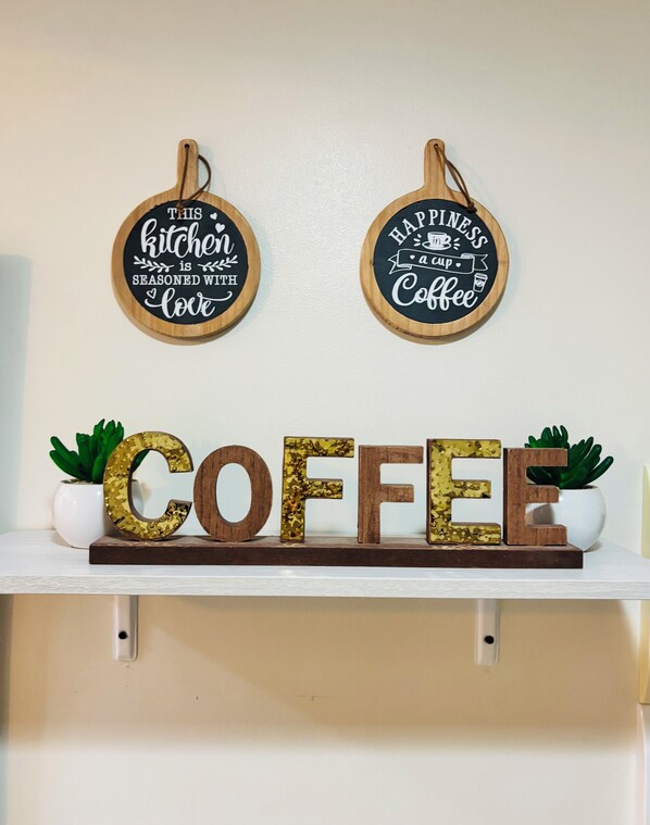 Two wooden signs with kitchen and coffee-related phrases, and the word "COFFEE" in large letters on a shelf. - Room-spectacular Escape to Relax and Unw (Iloilo)