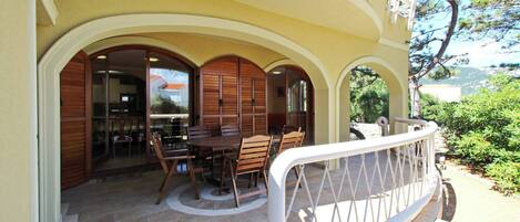 A covered outdoor seating area with a table and chairs, a wooden fence, and a view of the surrounding landscape.