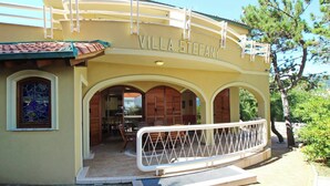 En byggnad som heter ”Villa Stefany”, med en täckt uteplats och ett vitt räcke.