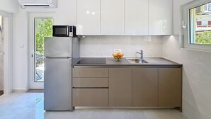 Une cuisine moderne équipée d’un four à micro-ondes encastré, d’un évier et d’un petit plan de travail.