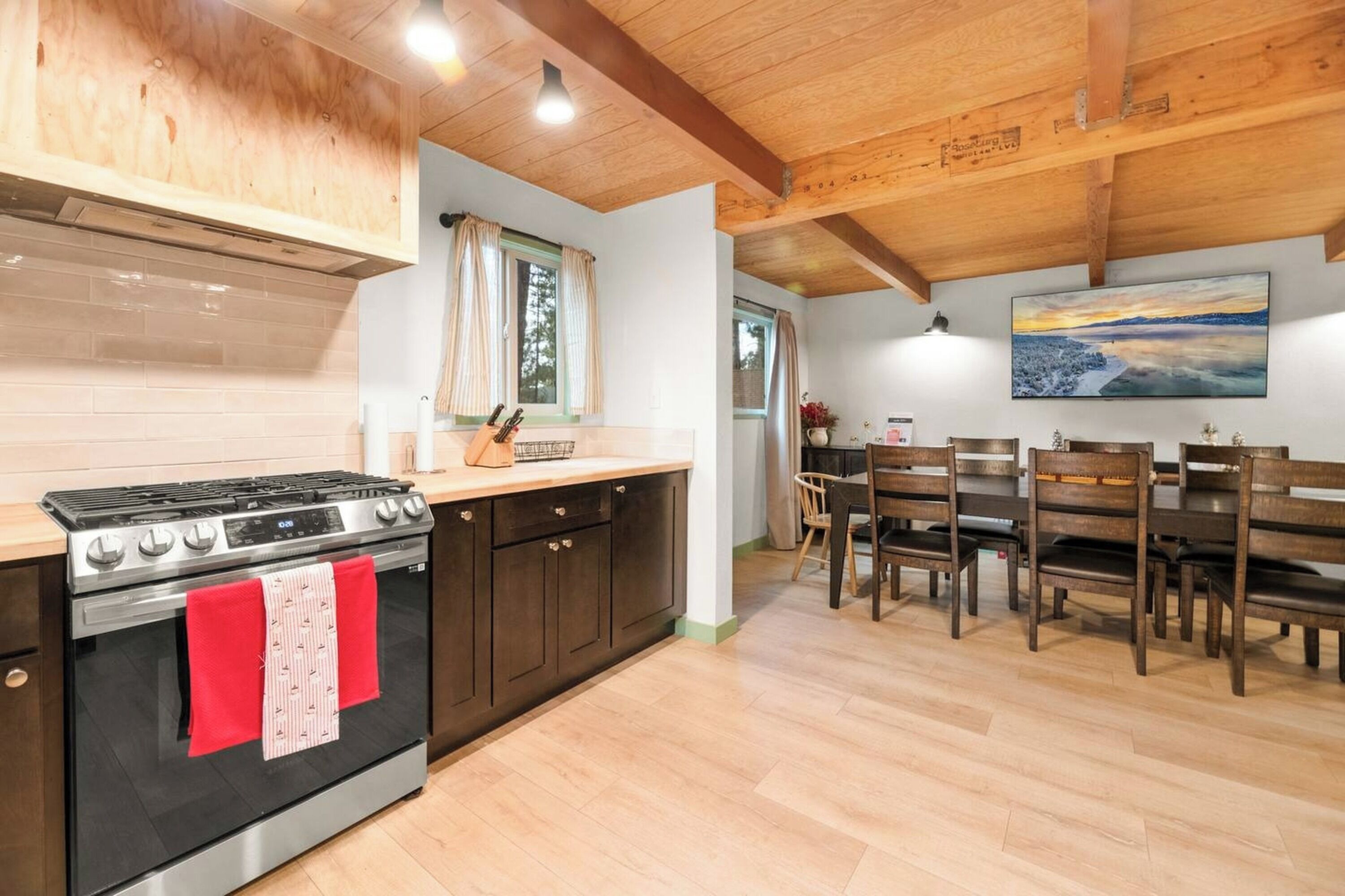 A kitchen with a stove, cabinets, and a dining area with chairs and a table.