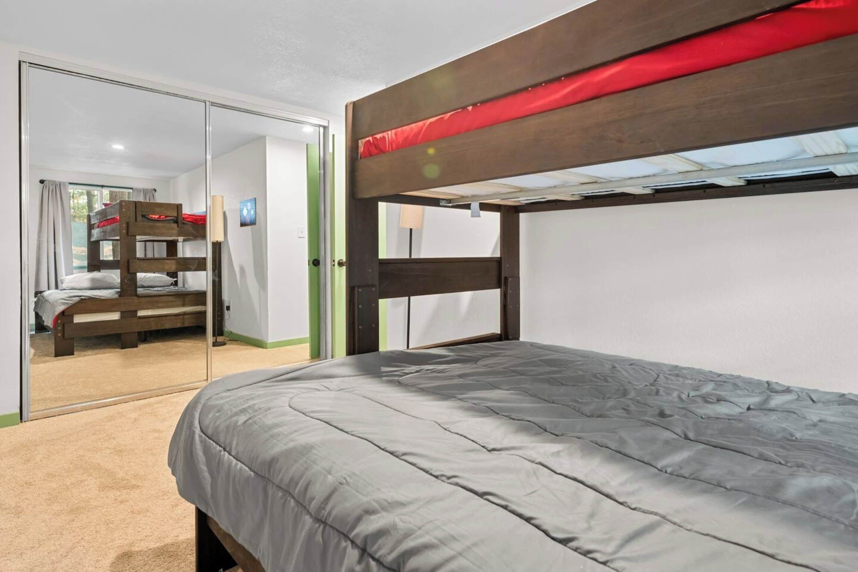 Een slaapkamer met een stapelbed, een enkel bed en een spiegel.