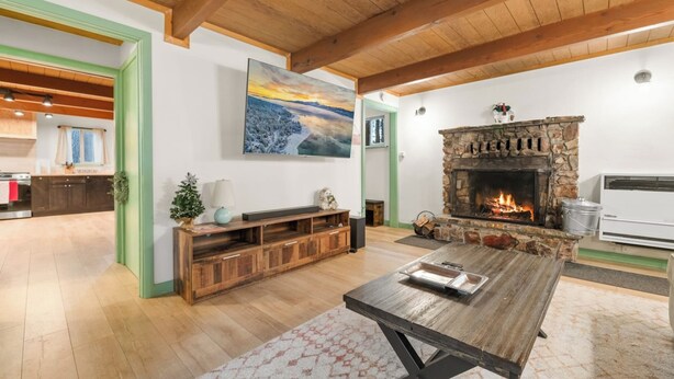 A cozy living room with a fireplace, wooden furniture, and a painting of a landscape. - Charming Cabin Escape (Big Bear Lake)