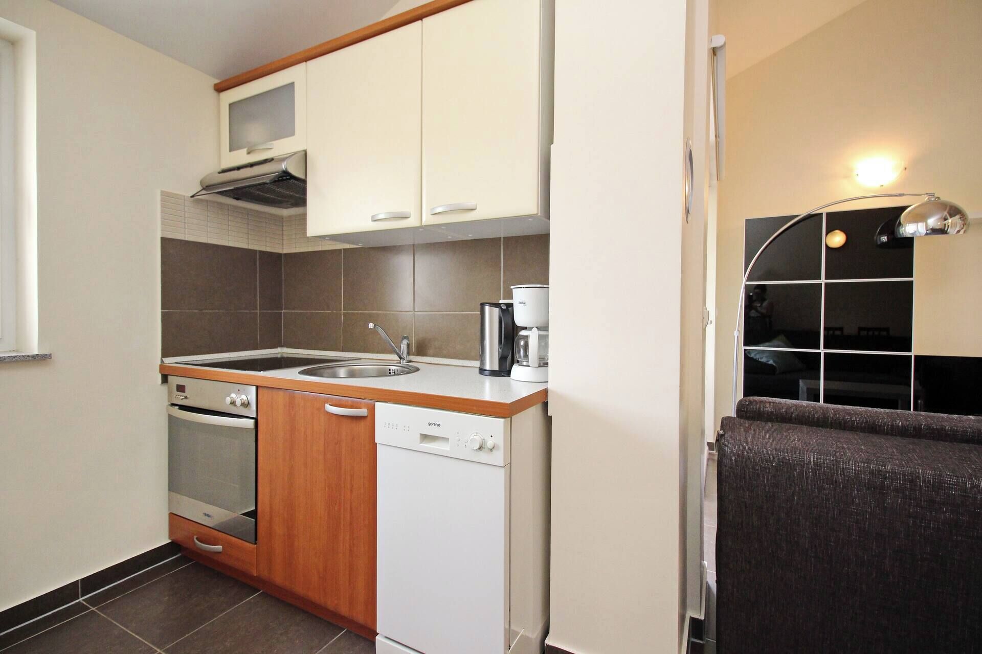 A compact kitchen with a stove, oven, dishwasher, and a sink.