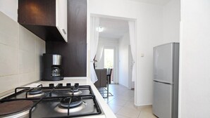 A modern kitchen with a gas stove, a coffee maker, and a stainless steel refrigerator. - Apartment Lara K1 - near the Center and the Beach (Baska)