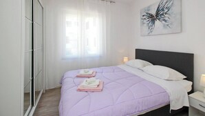 A bedroom with a bed, a nightstand, a wall-mounted artwork, and a window with sheer curtains. - Apartment Lara K1 - near the Center and the Beach (Baska)