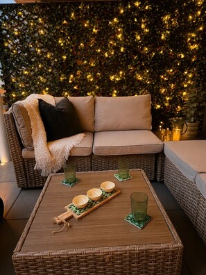 A wicker sofa with cushions and a tray with bowls and glasses on a wooden table. - Cosmo’s Getaway | Mtn Views | AC | BBQ | King Bed (Golden)