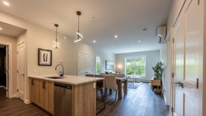 A modern kitchen with a central island, wooden cabinetry, and pendant lighting. - Cosmo’s Getaway | Mtn Views | AC | BBQ | King Bed (Golden)