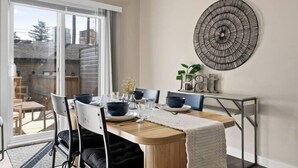 A dining area with a wooden table, black chairs, a chandelier, and a wall-mounted decorative piece.