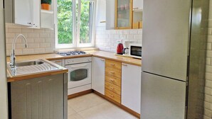 A modern kitchen with white cabinets, a stainless steel refrigerator, a gas stove, and a microwave.