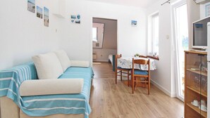 Un salon comprenant un canapé, une table à manger avec des chaises et un meuble pour la télévision.