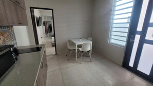 Una cocina pequeña y limpia con comedor, una ventana con persianas y una puerta con manija.