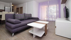 A modern living room with a purple sofa, a white coffee table, and a TV on a white cabinet. - Apartment Smojver No.4 - comfortable, with Balcony (Baska)
