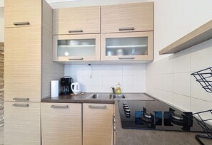 A modern kitchen with wooden cabinets, a stainless steel sink, and a black countertop.