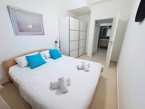 A hotel room with a bed, a wardrobe, a bathroom, and a framed picture on the wall.