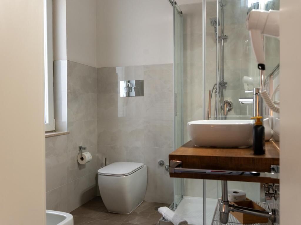 Un baño moderno con cabina de ducha de vidrio, un inodoro y un lavabo con encimera de madera.