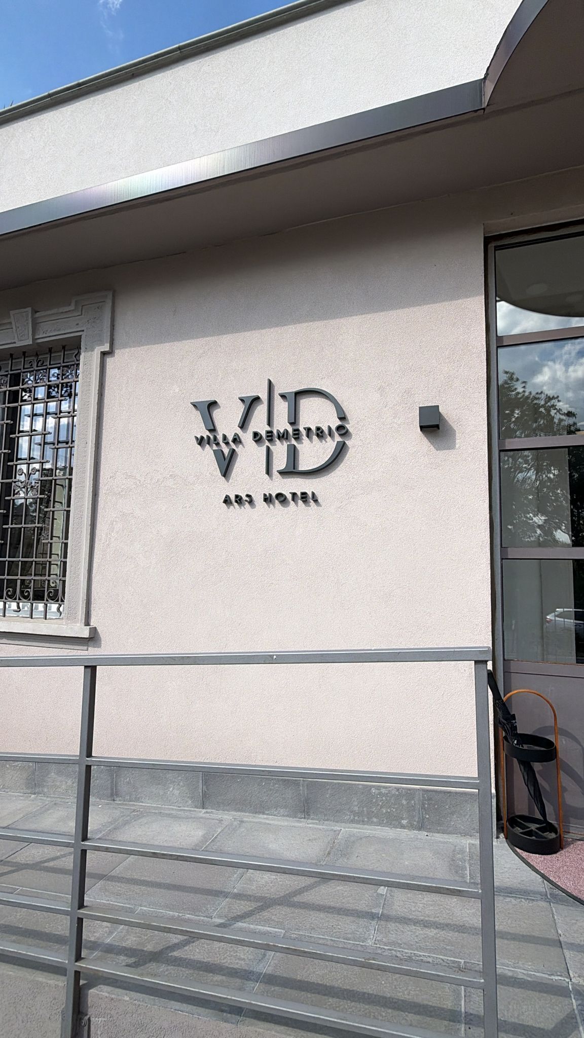 A building facade with a large, bold logo and the name 'Villa Demetrio Art Hotel' in capital letters.