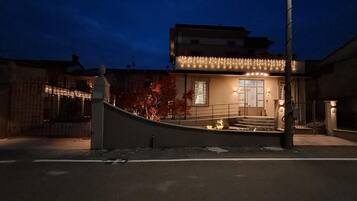 Un edificio con una entrada curva, una escalera que lleva a una puerta y una fachada bien iluminada.