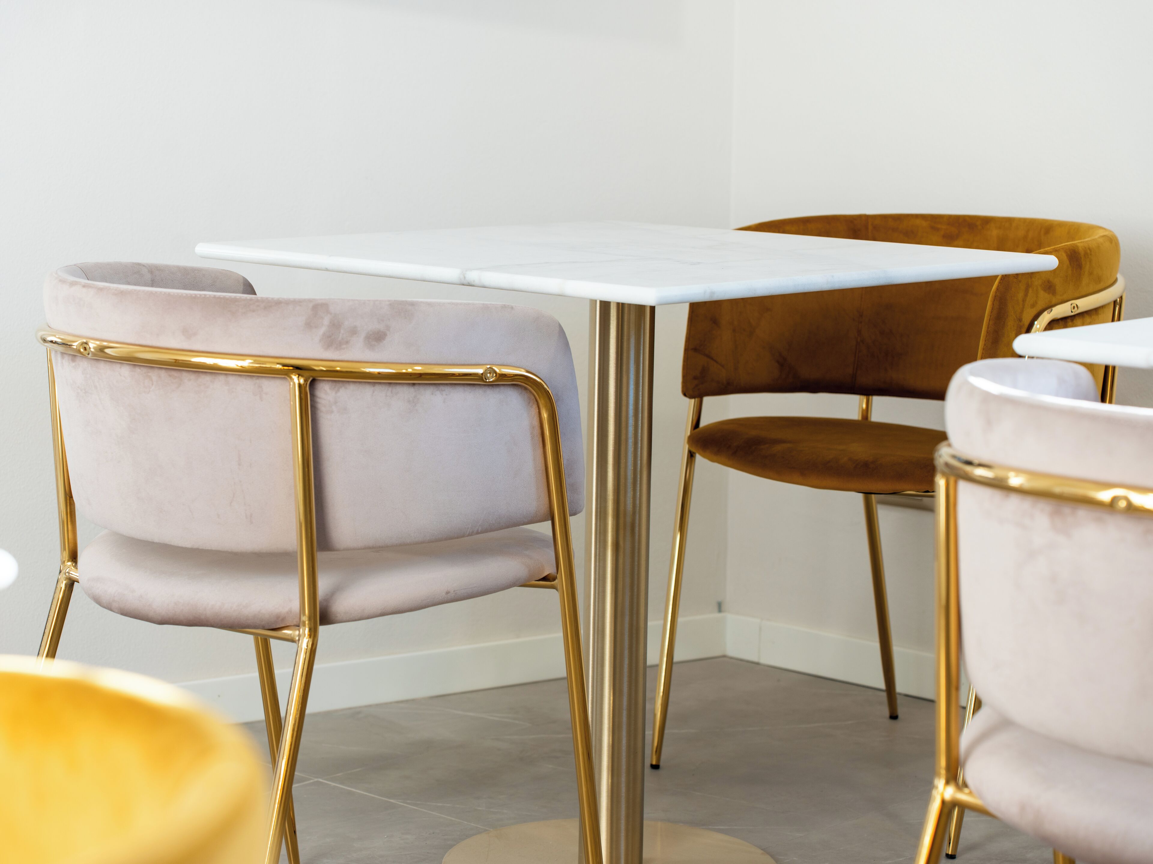 Een moderne eetruimte met een marmeren tafel en stoelen met goud- en bruine bekleding.