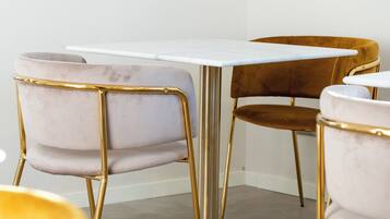 Een moderne eetruimte met een marmeren tafel en stoelen met goud- en bruine bekleding.