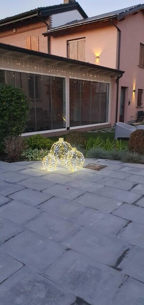 A house with a large glass door, a light fixture on the wall, and a decorative light structure in the yard. - Villa Demetrio Ars Hotel (San Rocco al Porto)