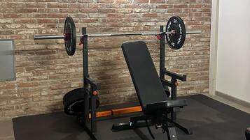 A gym with a brick wall, a bench press, and a squat rack.