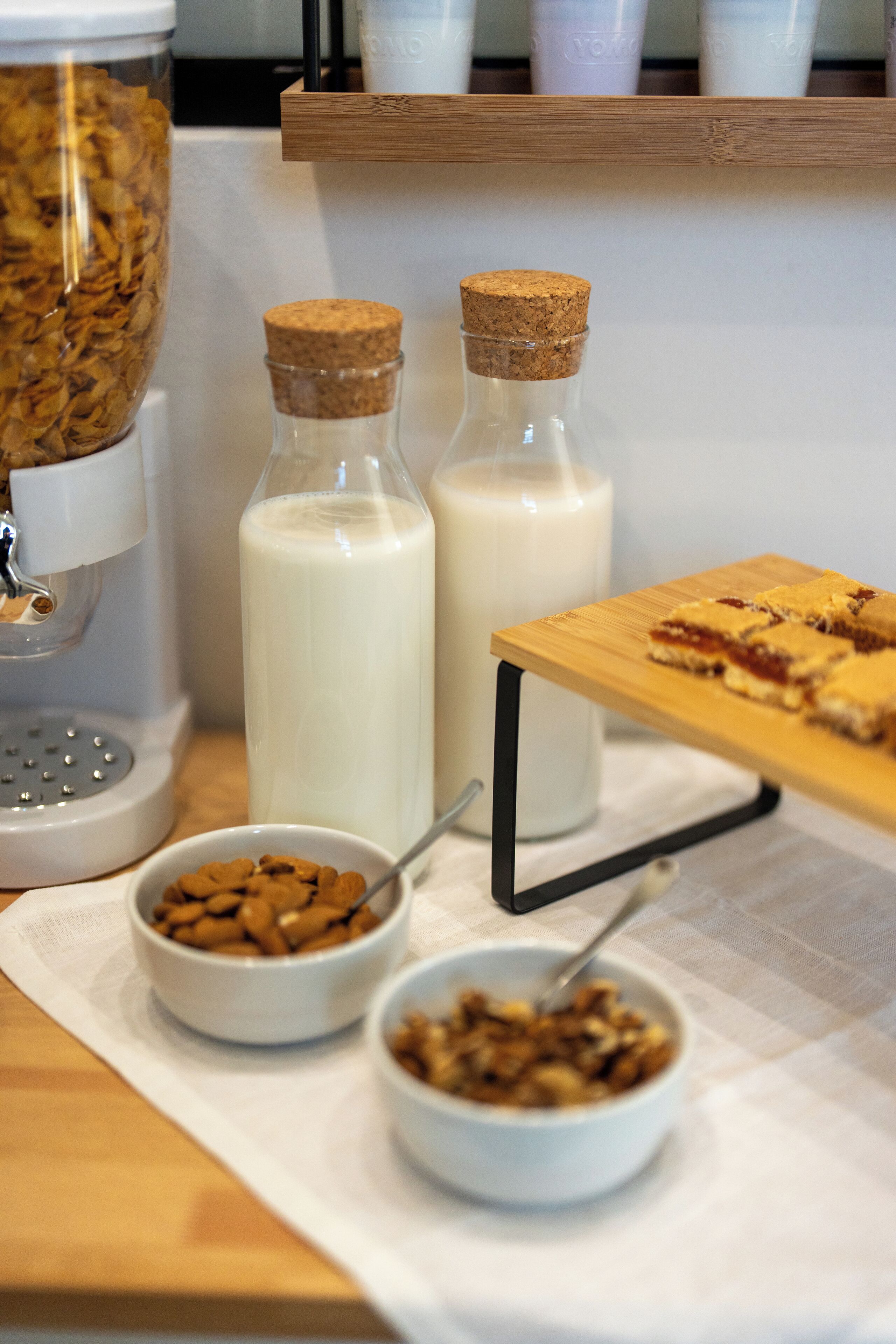 Desayuno con una cafetera, dos botellas de leche y tazones de cereal y granola.
