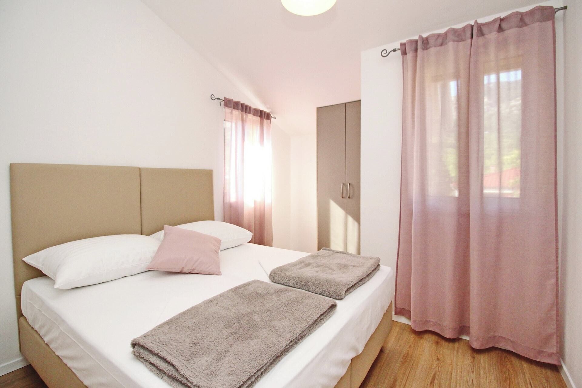 A bedroom with a bed, two pillows, a bedside table, and a wardrobe.
