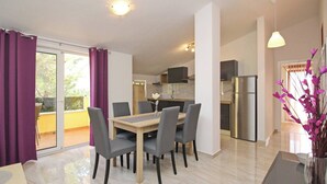Un apartamento moderno con comedor, cocina y un balcón con cortinas moradas.