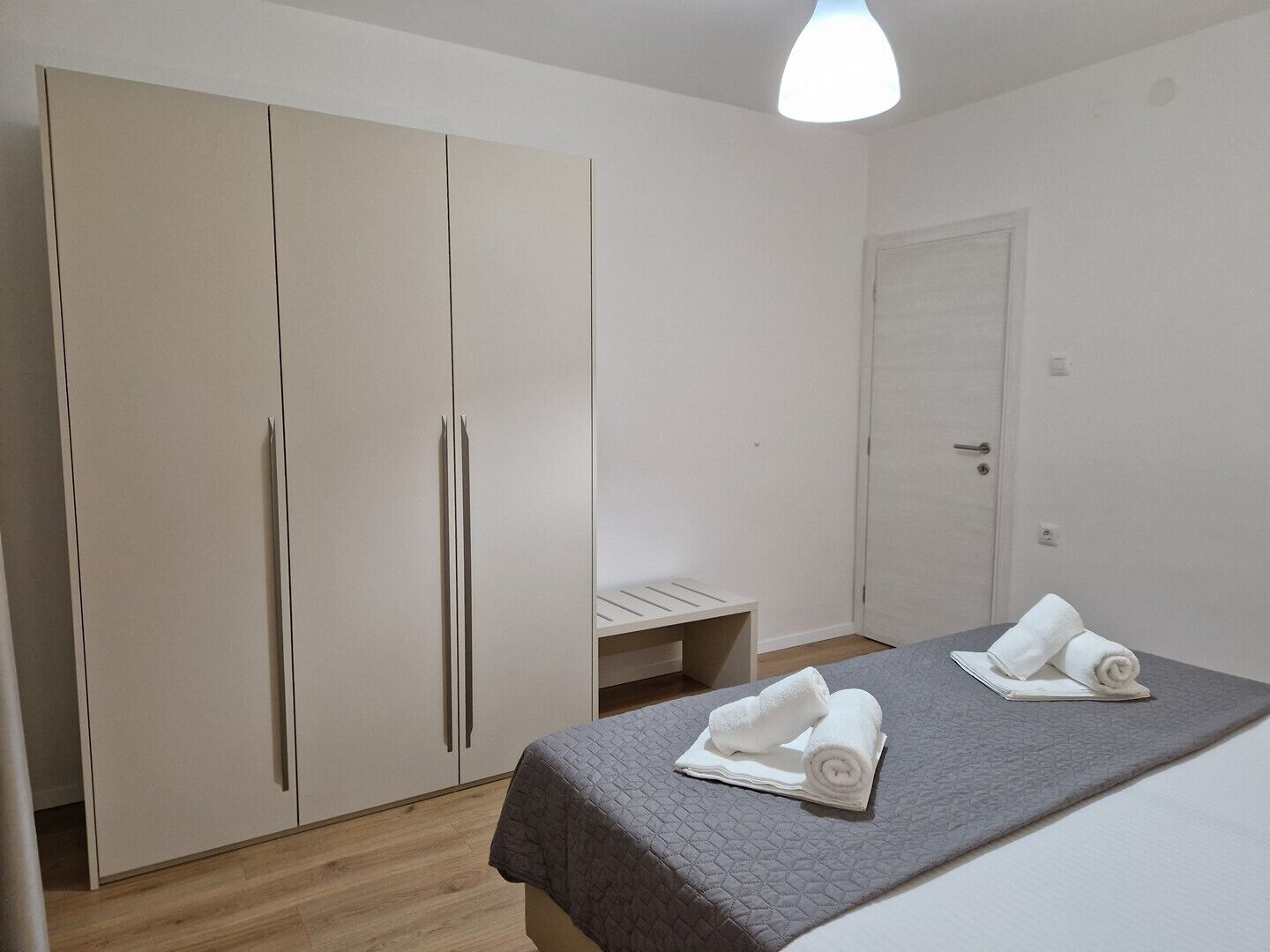 Een slaapkamer met een bed, een kledingkast en een bankje.
