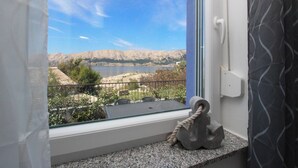 Une fenêtre donnant sur un paysage montagneux et un plan d’eau.