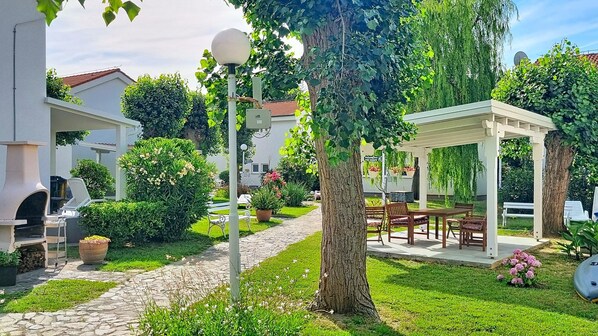 A garden with a gazebo, outdoor seating, and a stone pathway.