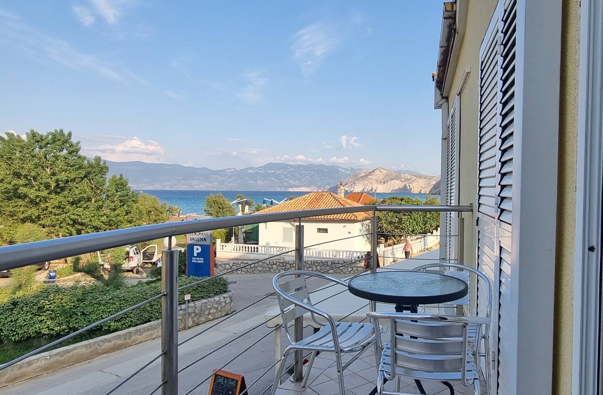 A balcony with a table and chairs, a view of the sea, and a parking sign.