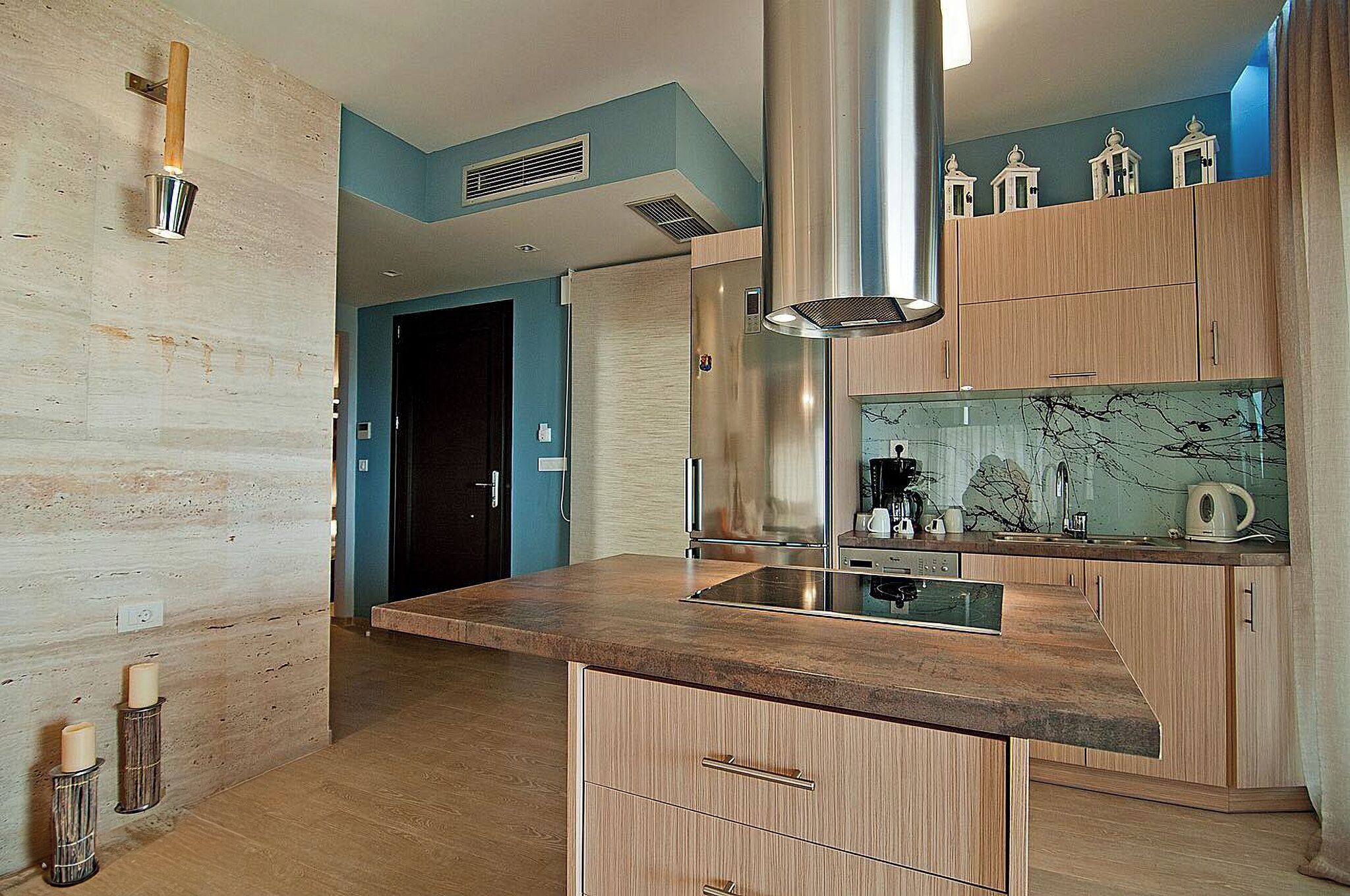 A modern kitchen with wooden cabinets, a marble backsplash, and a stainless steel range hood.