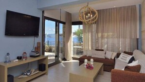 A modern living room with a flat-screen TV, a wooden console table, a sofa, and a coffee table. - Christie's Luxury Suites (Igoumenitsa)