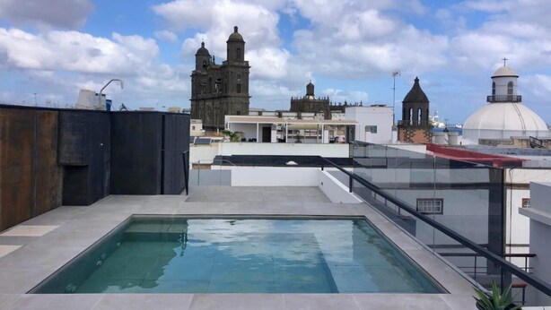Una piscina en la azotea con vistas a edificios históricos al fondo.