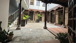 Un patio cubierto con piso de piedra, plantas en macetas y una escalera de madera.
