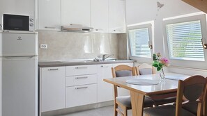 Eine moderne Küche mit weißen Schränken, einer eingebauten Mikrowelle und einem Essbereich mit Tisch und Stühlen.